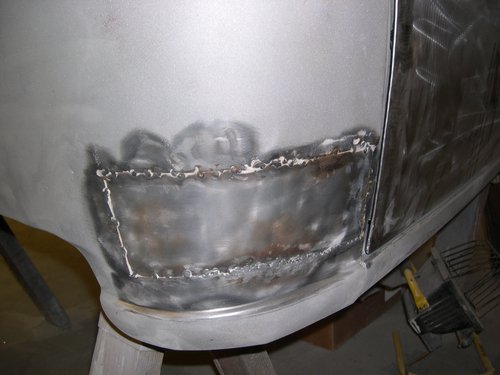   BEFORE: Here's what showed up in the lower rear cab corner once old body filler was removed. Pretty grim--flat panel, lap welds, seam sealer covered up in lots of Bondo.  